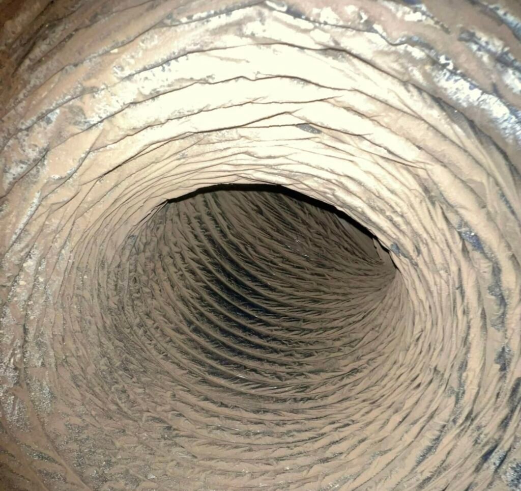 Dust and debris on the interior surfaces of an air duct before cleaning
